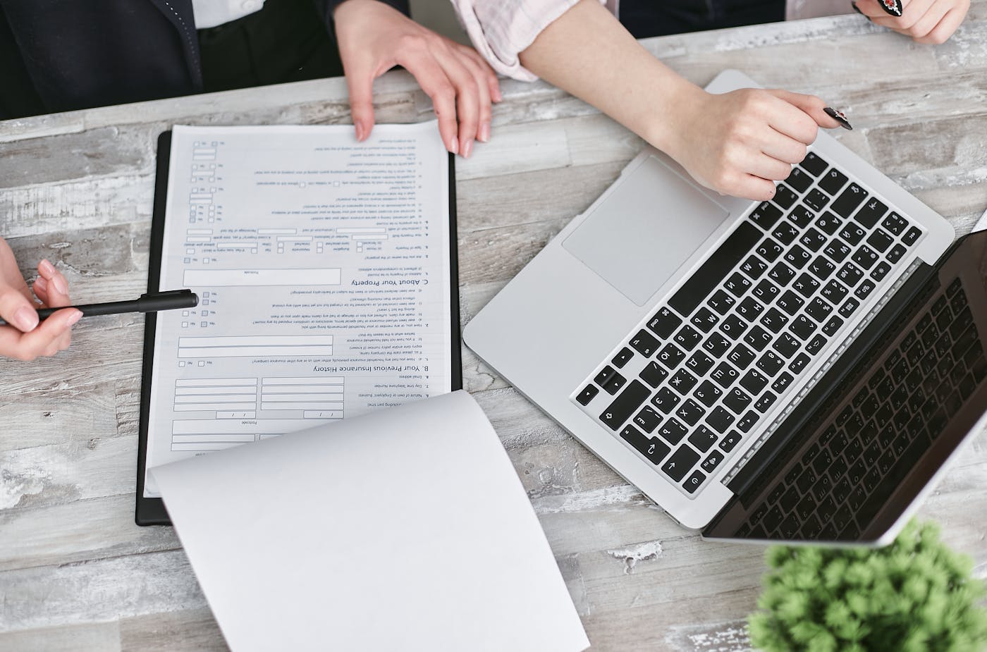 People reviewing documents beside a laptop during a business workflow discussion.